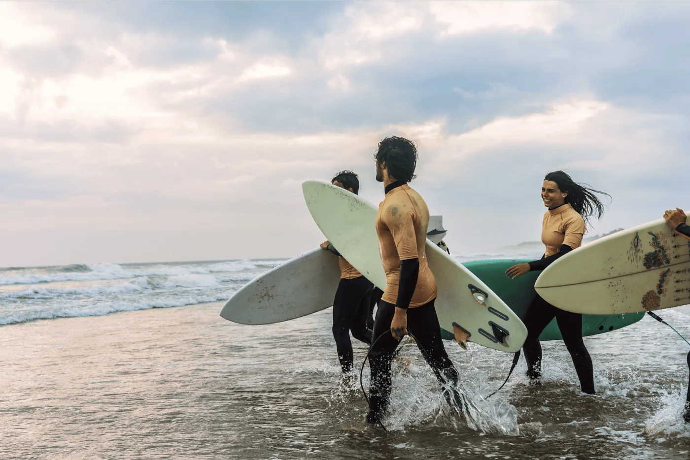 Estudiantes de surf entrando al mar con sus tablas